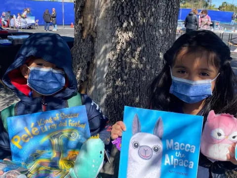 a couple of kids wearing masks and holding up some paper
