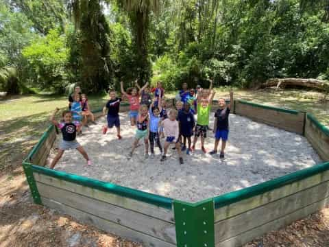 a group of children standing on a wooden bridge over a river