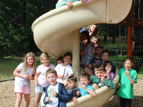 a group of children posing for a photo in front of a slide