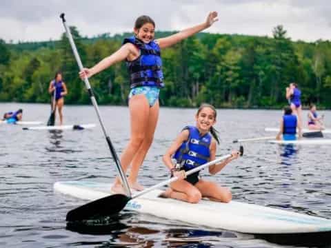 a couple of girls on a paddle board in the water