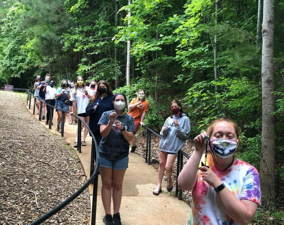 a group of people walking on a trail in the woods