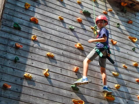 a boy climbing a wooden wall