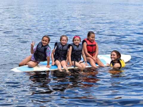 a group of girls on a surfboard in the water