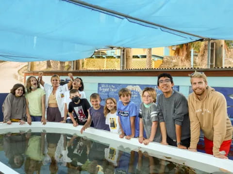 a group of people posing for a photo next to a large pool