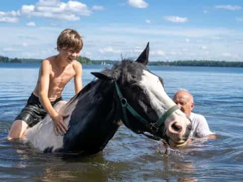 a man and a boy riding a horse in water