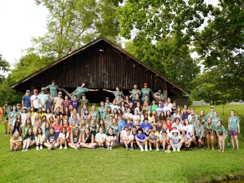 a group of people posing for a photo in front of a log cabin