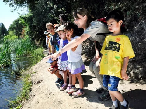 a group of children standing on a path by a river