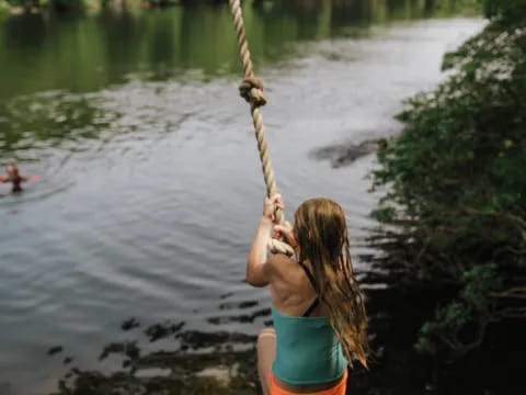 a woman holding a rope over a body of water