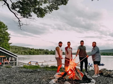 a group of men standing around a fire on a rocky beach