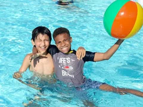 a person and a boy in a pool with a ball
