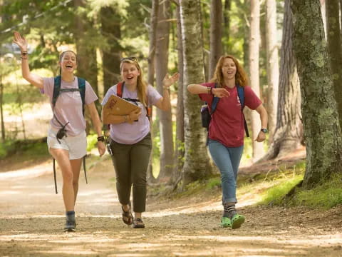 a group of women running on a trail in the woods