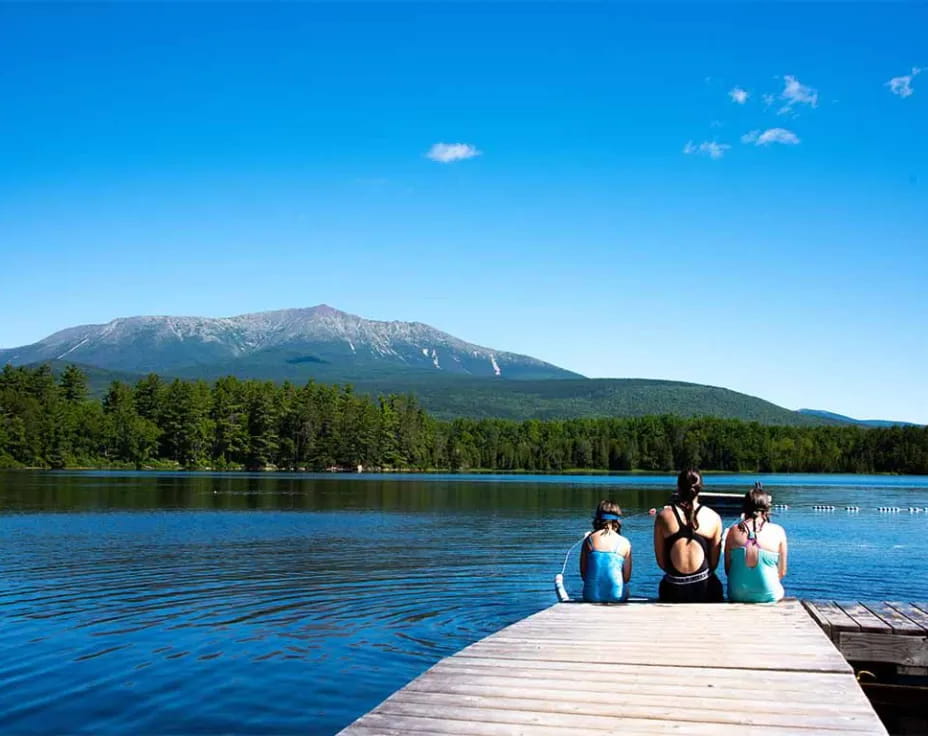 a group of women sitting on a dock by a lake