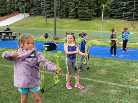 a group of kids playing with a bow and arrow