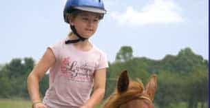 a child wearing a helmet and riding a horse