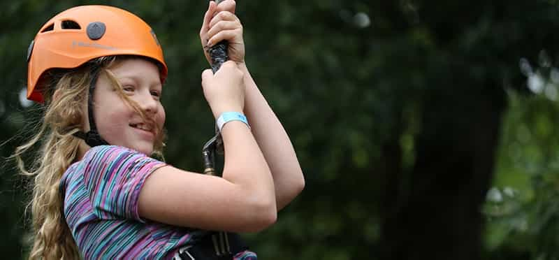 a girl wearing a helmet and holding a rope