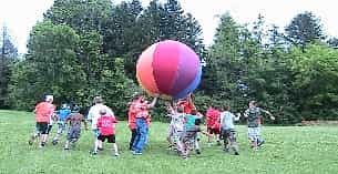 a group of children running with a large red balloon