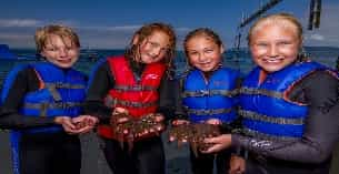 a group of people in life jackets holding a fish