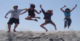 a group of people jumping in the air on a beach