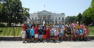 a group of people posing for a photo in front of a white house