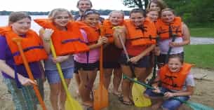 a group of people wearing life vests and holding sticks