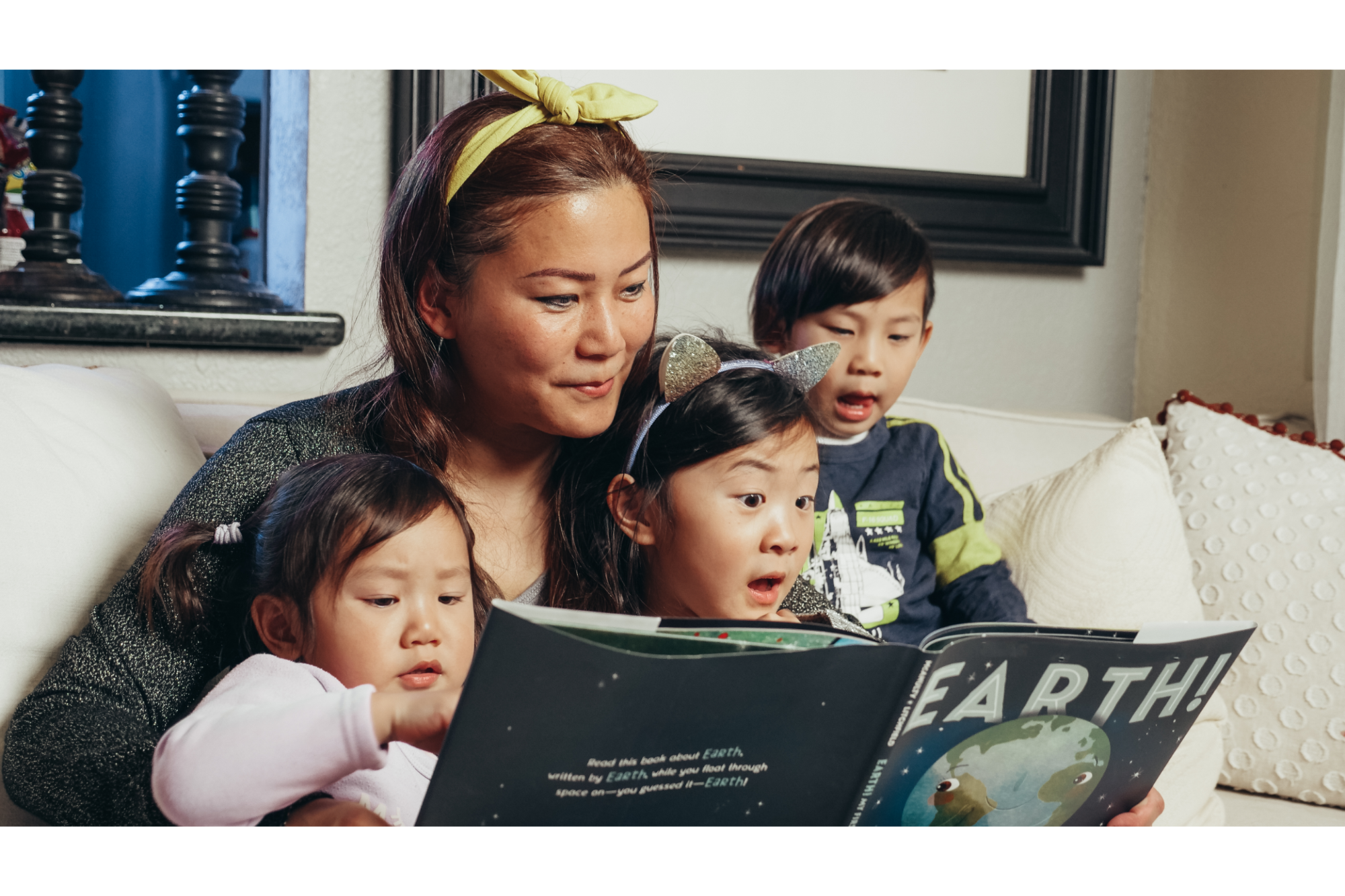 a woman and several children sitting on a couch looking at a laptop
