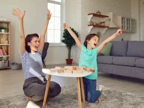 a couple of girls playing with sticks in a living room