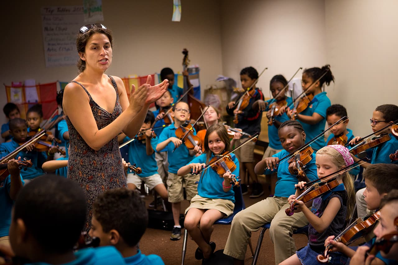 a person standing in front of a group of kids playing instruments