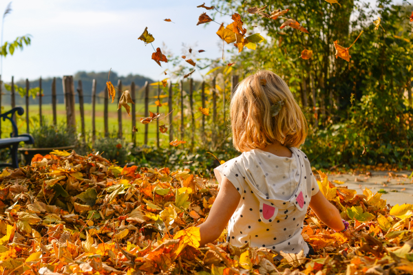 a little girl sitting in a pile of leaves