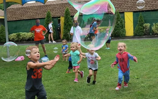 a group of children running in a yard with a large bubble