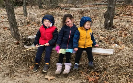 a group of children sitting on a log in the woods