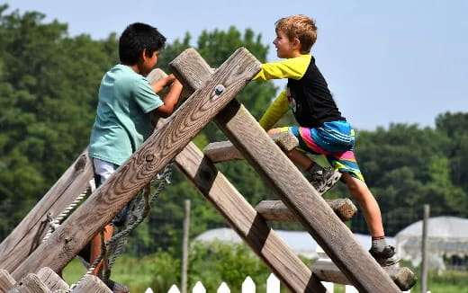 a couple of boys playing on a wooden structure