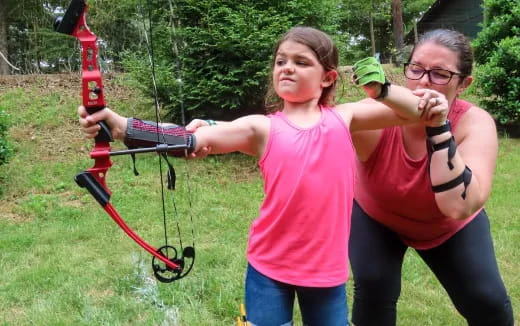 a person and a girl playing with a bow and arrow