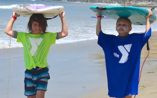 kids holding surfboards on beach