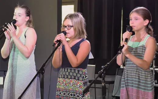 a group of women singing into microphones