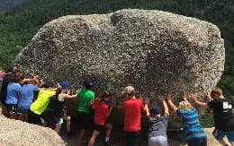 a group of people standing in front of a large rock