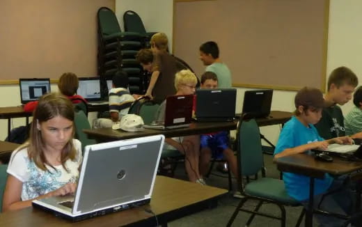 a group of people sitting at desks with laptops