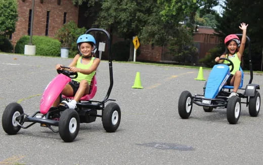 two kids riding on small wheeled vehicles