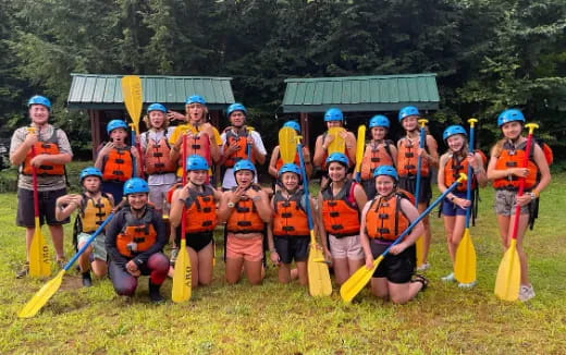 a group of people wearing life vests and holding sticks