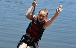 a child on a life jacket holding onto a rope in the water