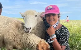 a girl smiling next to a couple of sheep
