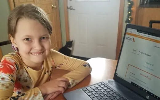 a child sitting at a table with a laptop