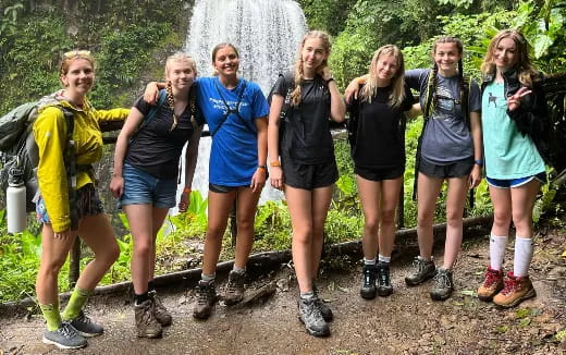 a group of people posing for a photo in front of a waterfall