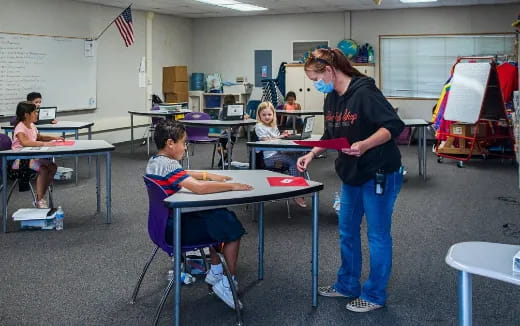 a person standing in front of a classroom with a group of children