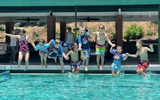 a group of children jumping into a pool
