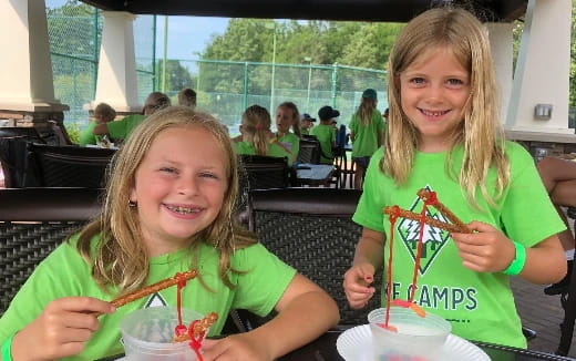 a couple of girls smiling and eating food