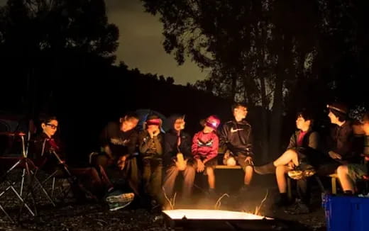 a group of people sitting around a campfire at night