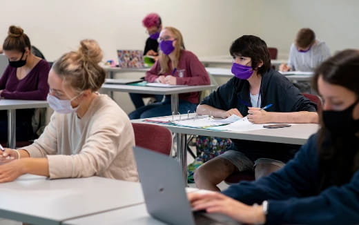 a group of people sitting at desks in a classroom