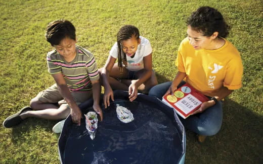 a group of kids playing with a plastic ball in the grass