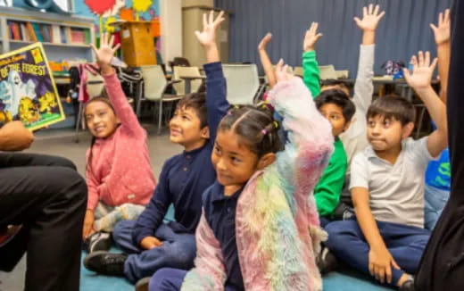 a group of children raising their hands