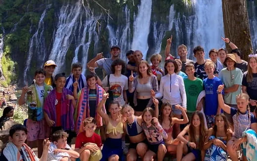 a group of people posing for a photo in front of a waterfall